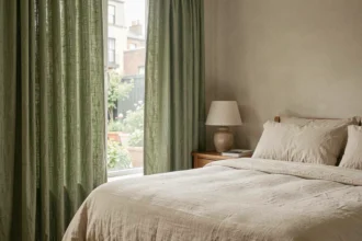 Chambre à coucher avec rideaux en lin vert sauge jusqu'au sol, literie ivoire et ambiance douce et cosy